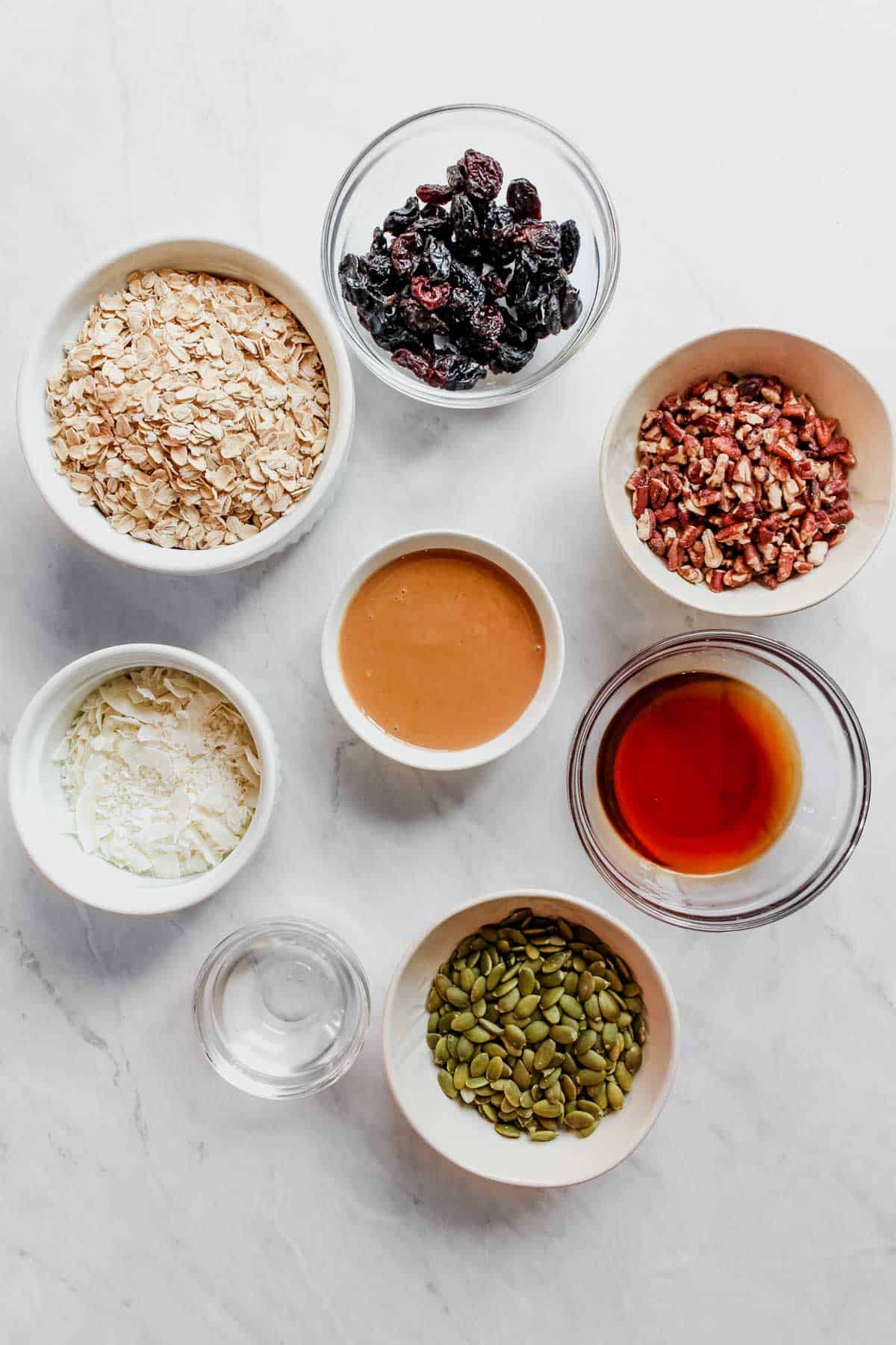Overhead view of individual granola ingredients in small bowls.