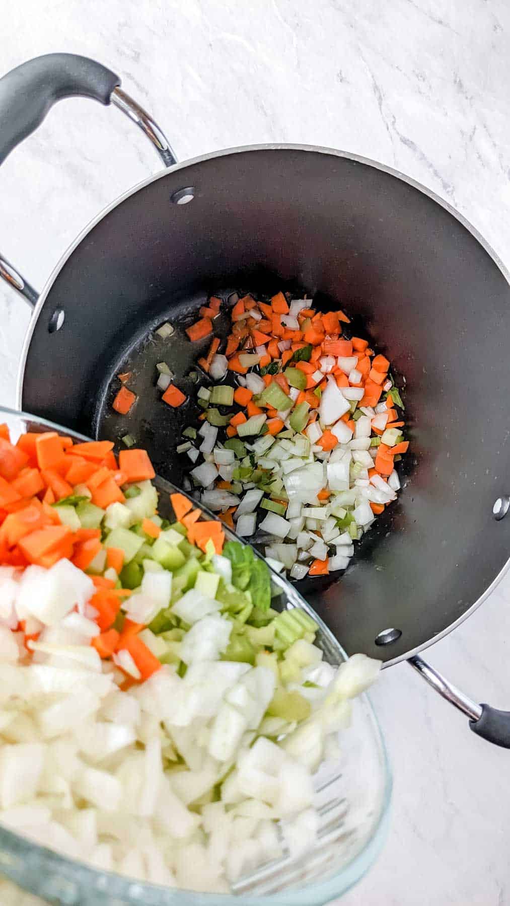 Adding in onions, celery, carrots to soup pot.