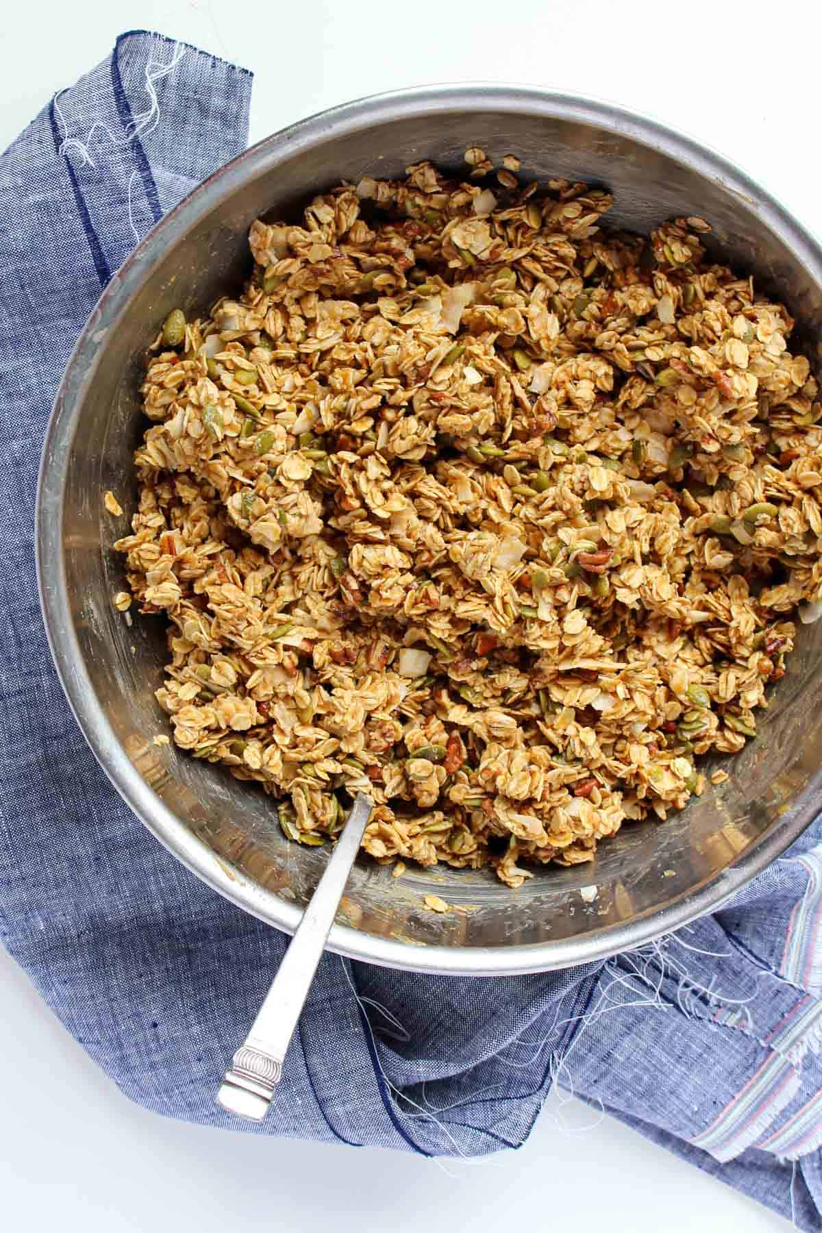 Wet and dry granola ingredients mixed in a stainless steel bowl