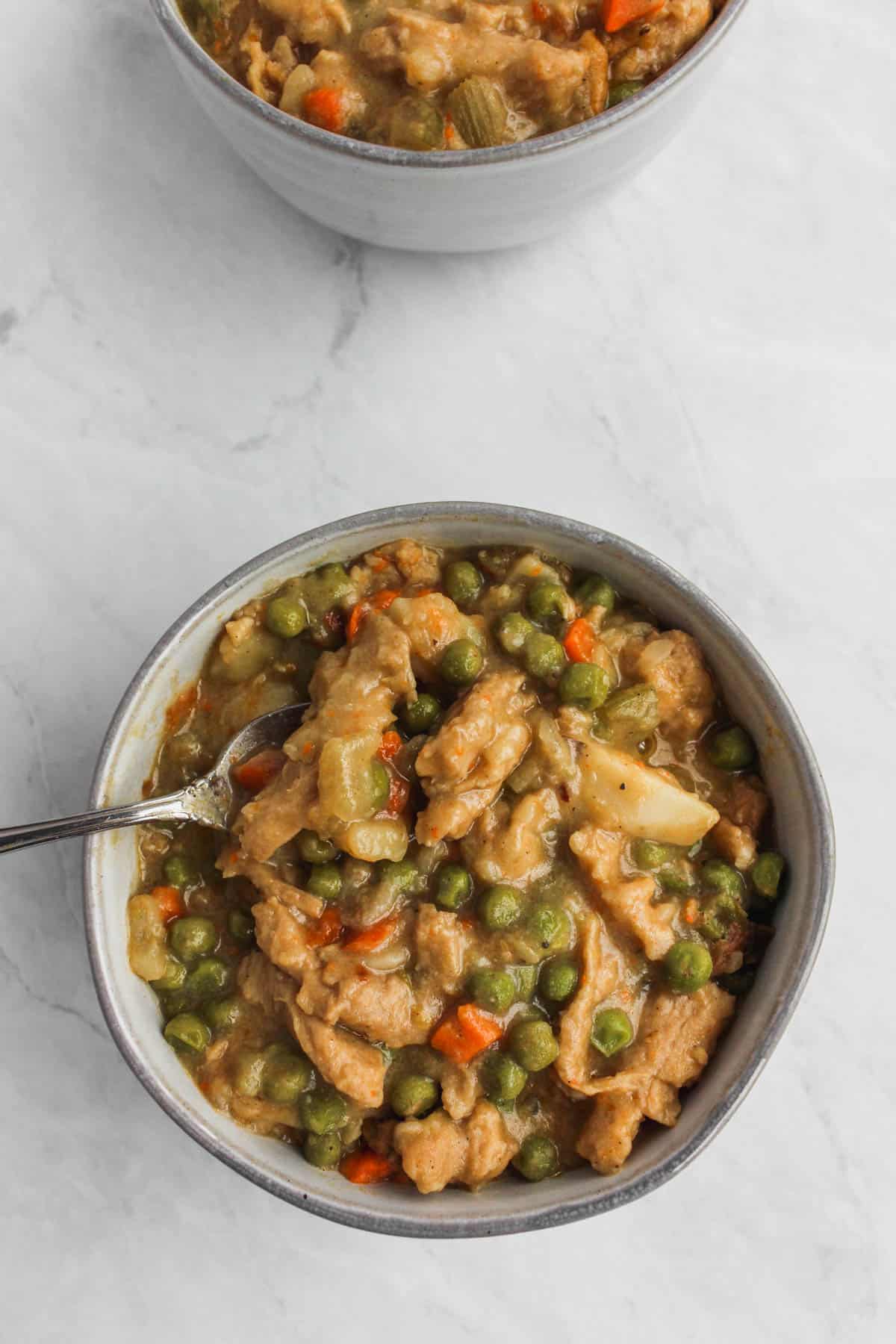 Bowl of vegan and chicken potato soup in grey bowl on marble background