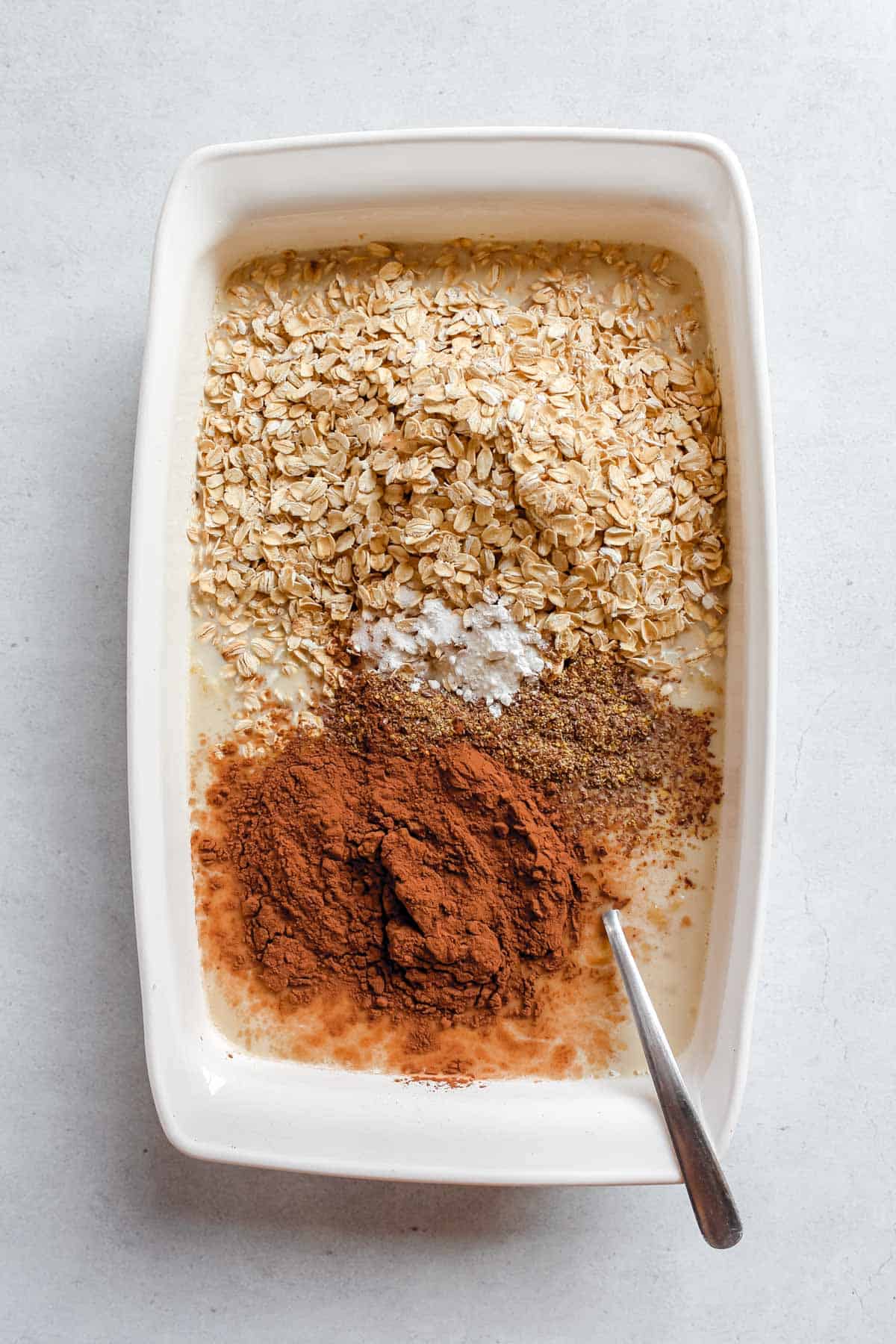 Rest of the ingredients including the rolled, cocoa powder, cinnamon, baking powder, salt and ground flaxseed added to white baking dish.