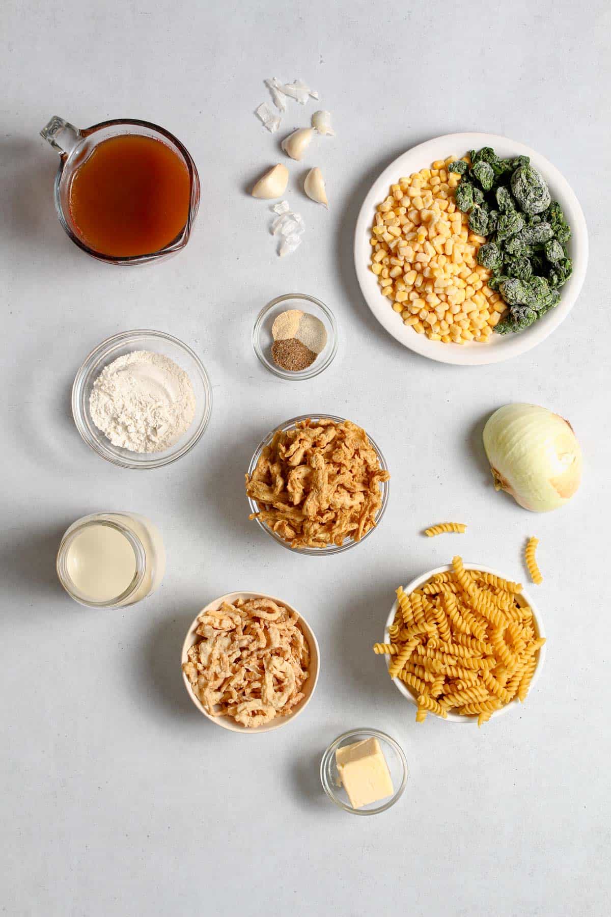 Individual, uncooked, ingredients in separate bowl for the casserole on a light grey background