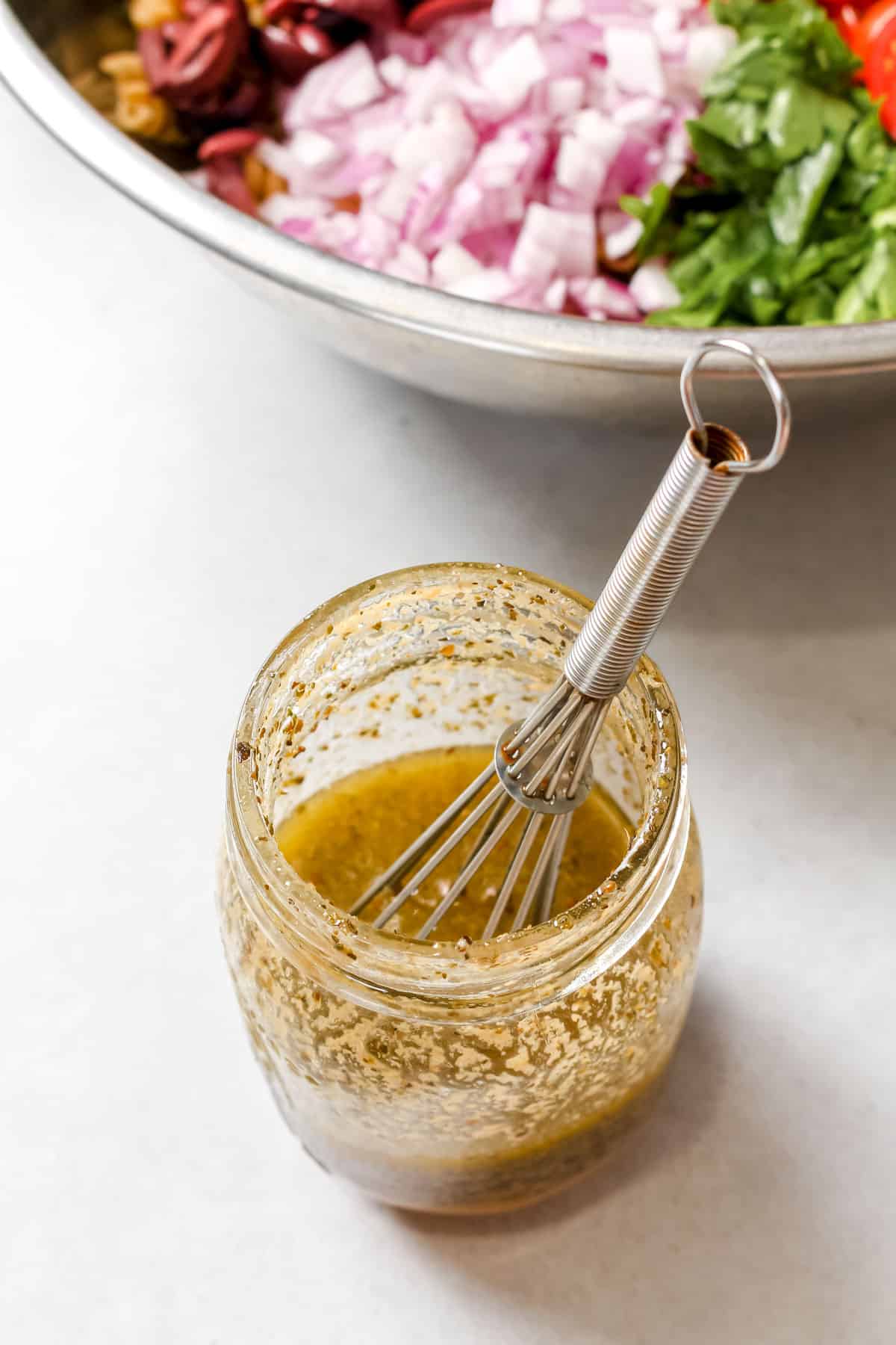 Homemade Italian dressing in glass jar with a small whisk