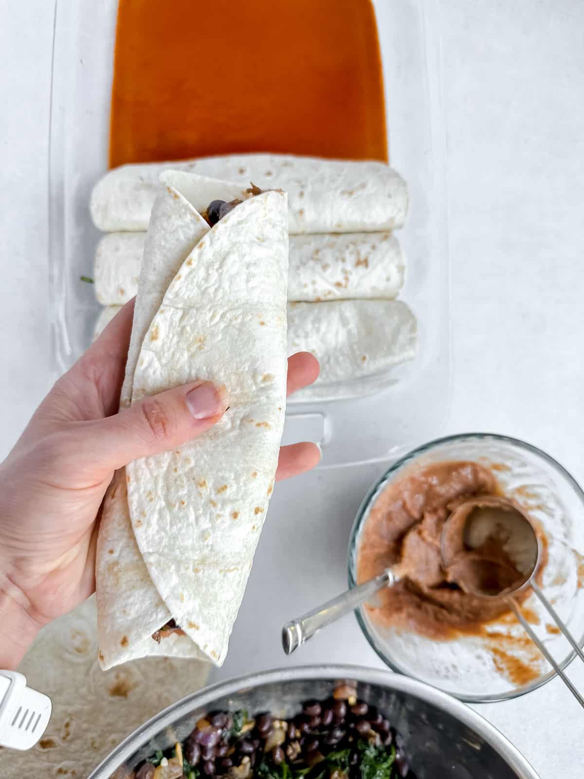 Hand holding a wrapped enchilada