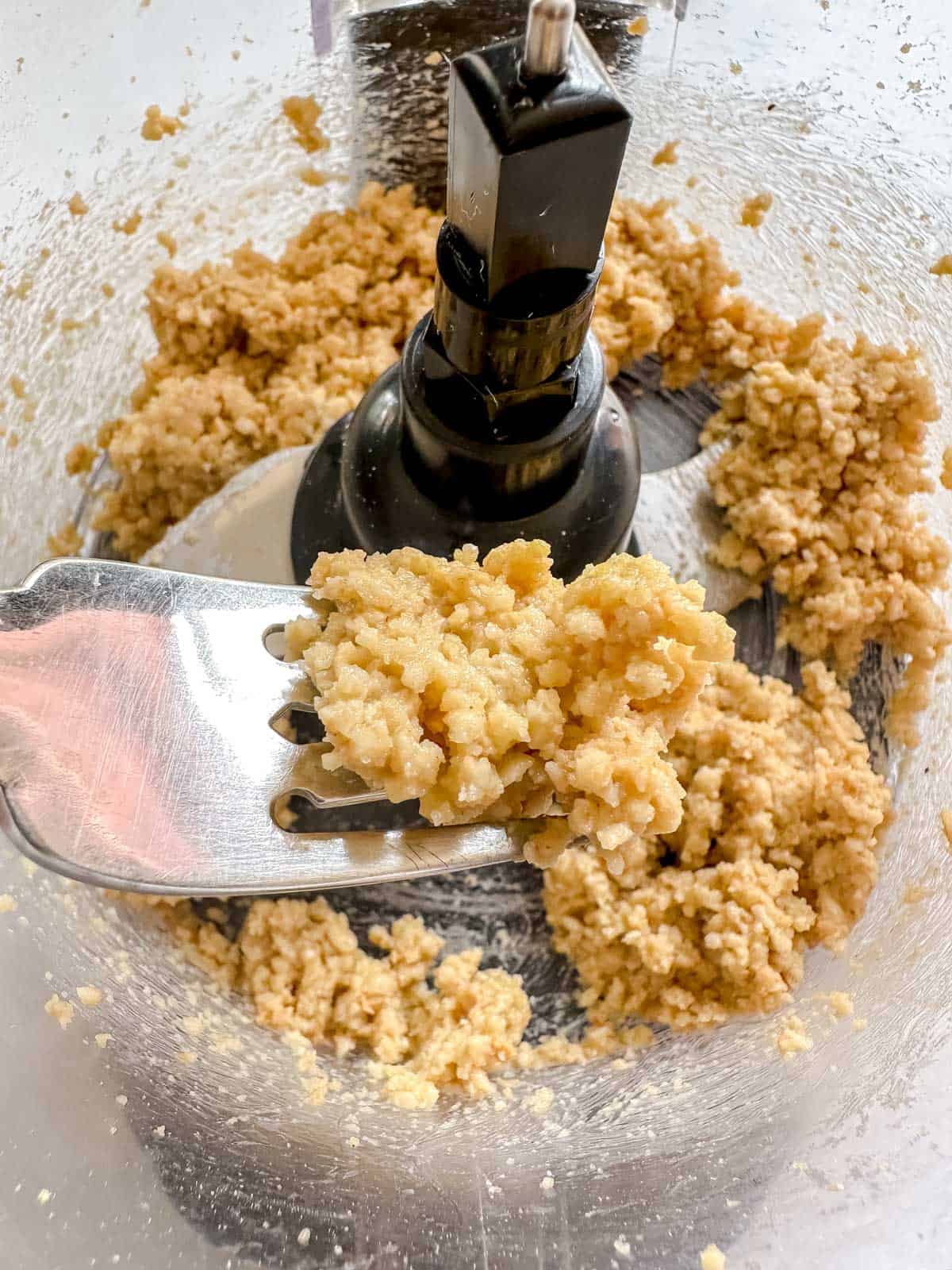 Crumbly Vegan cotija cheese inside food processor with some on a fork to show texture up close