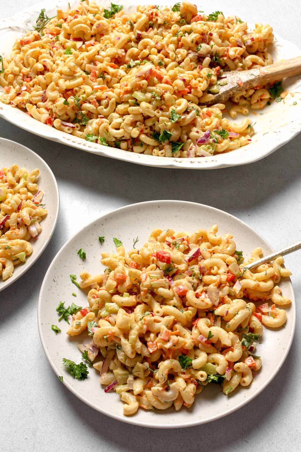 Vegan Macaroni Salad on white round plate and in a white serving platter