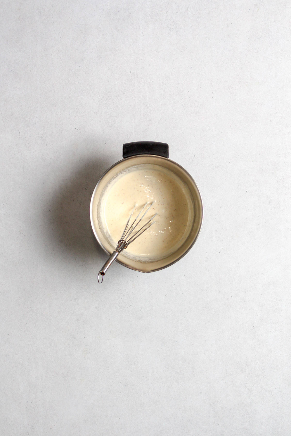Creamy Dill Pickle Salad Dressing in small mixing bowl with whisk.