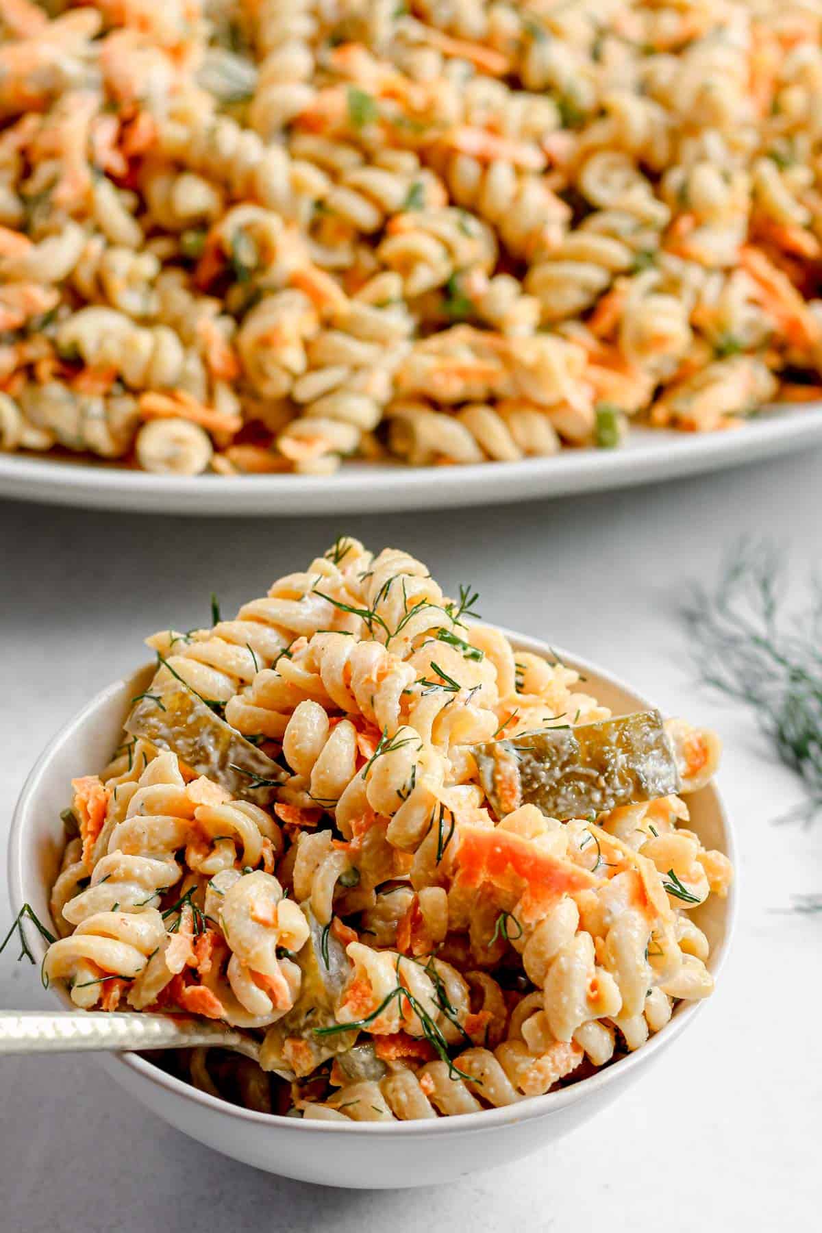 White bowl holding creamy vegan dill pickle salad