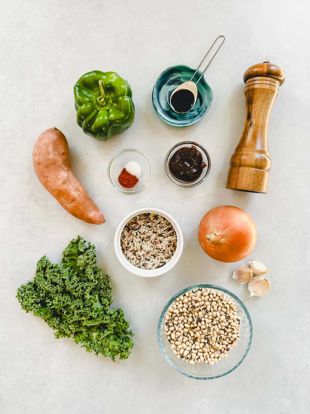 Individual ingredients measured out for this black-eyed pea soup on a white background