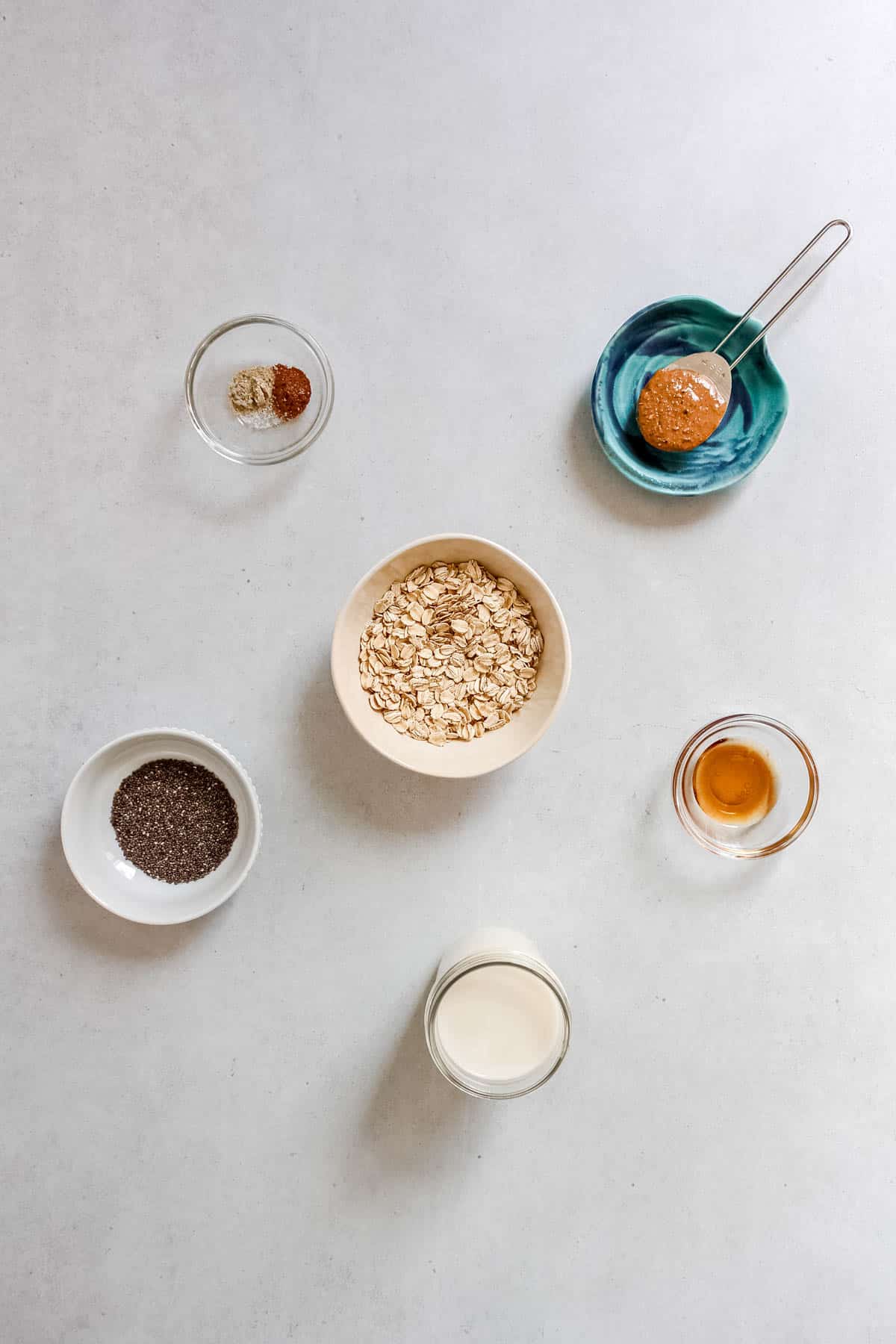 Individual cardamom overnight oat ingredients in bowls on a white background