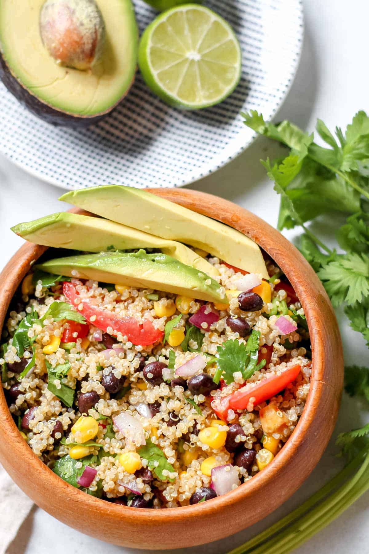Black Bean, Corn, and Quinoa Salad in a wooden bowl topped with three avocado slices