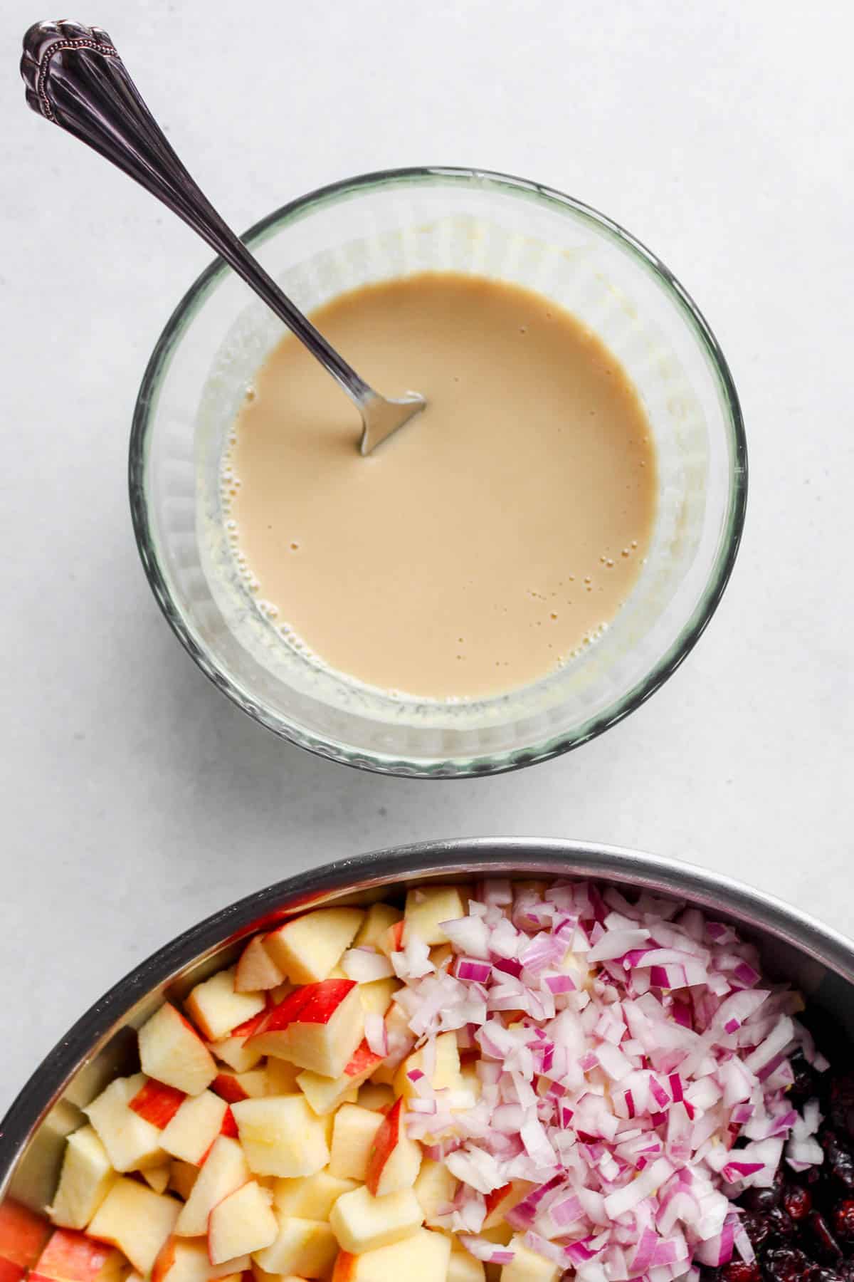 Creamy tahini dressing in a glass bowl with a fork for mixing, ready to be tossed with the salad ingredients.