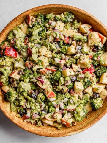 Vegan Broccoli Apple Salad served in a large brown ceramic bowl on a white background