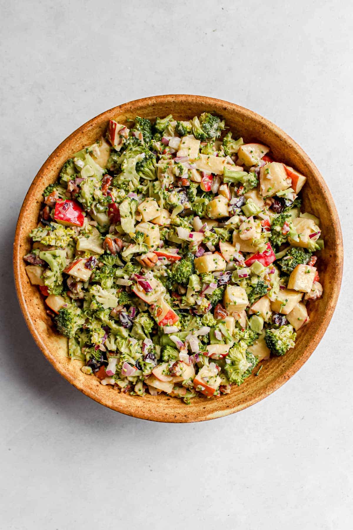 Vegan Broccoli Apple Salad served in a large brown ceramic bowl on a white background