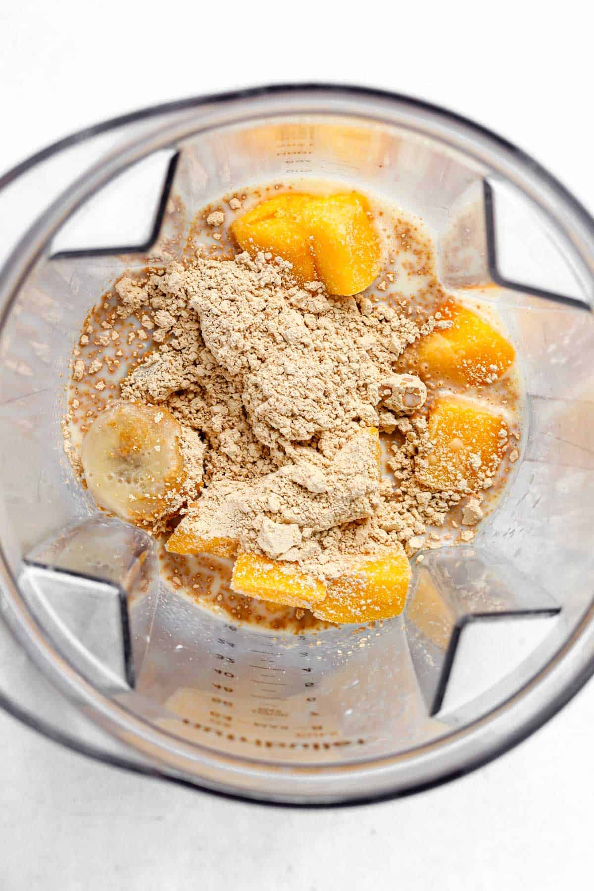 Soy milk, frozen banana, frozen mango and protein powder in blender.