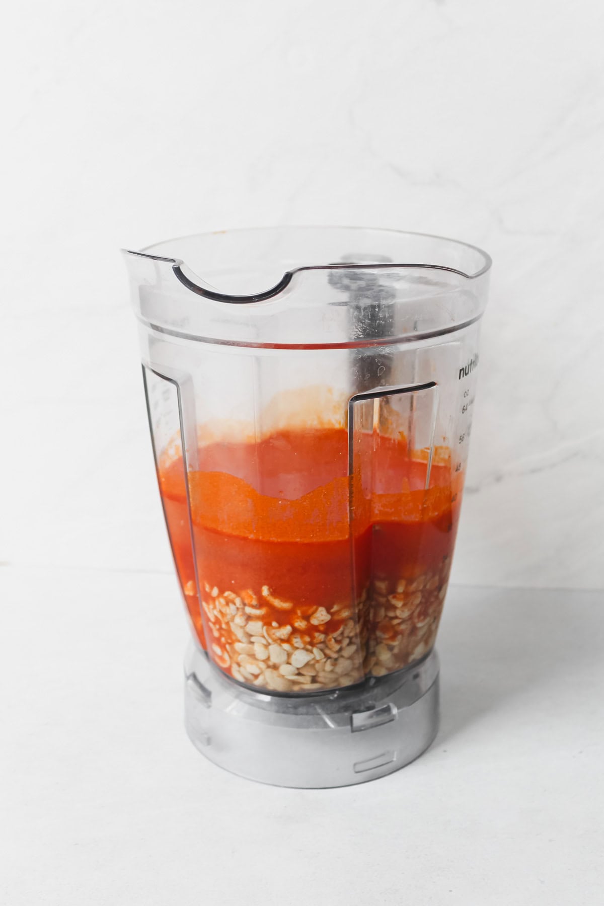 Cashews, water, and buffalo sauce in blender, prior to being blended.